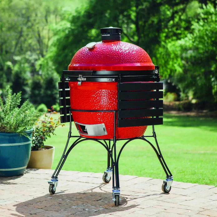 Kamado Joe Big Joe II 24-inch ceramic grill on cart with side shelves lowered on a patio shows the grills compact parked profile while still keeping the cooker ready to roll and use